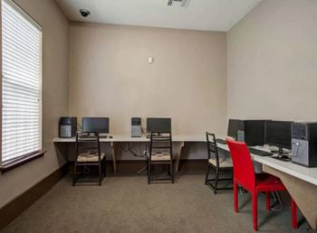 a computer room with three computers and a red chair